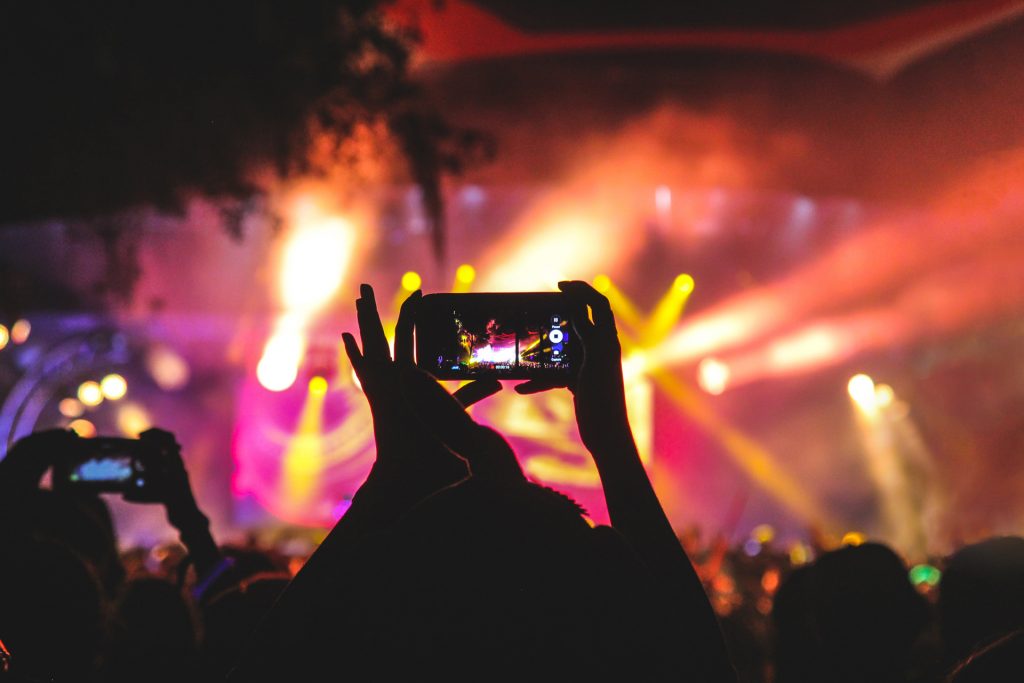 Personne utilisant son smartphone pour filmer un spectacle de nuit en extérieur